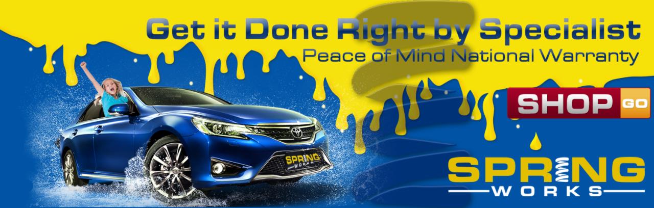 Reklama warsztatu samochodowego Spring Works z niebieskim samochodem i dzieckiem wystającym przez okno, z hasłami 'Get it Done Right by Specialist' i 'Peace of Mind National Warranty'...