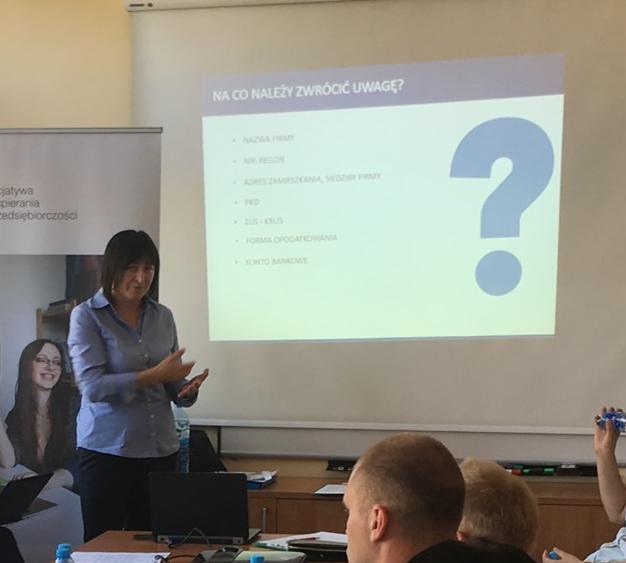 Prezentacja na temat czynników, na które należy zwrócić uwagę przy zakładaniu firmy, prowadzona przez kobietę podczas spotkania.