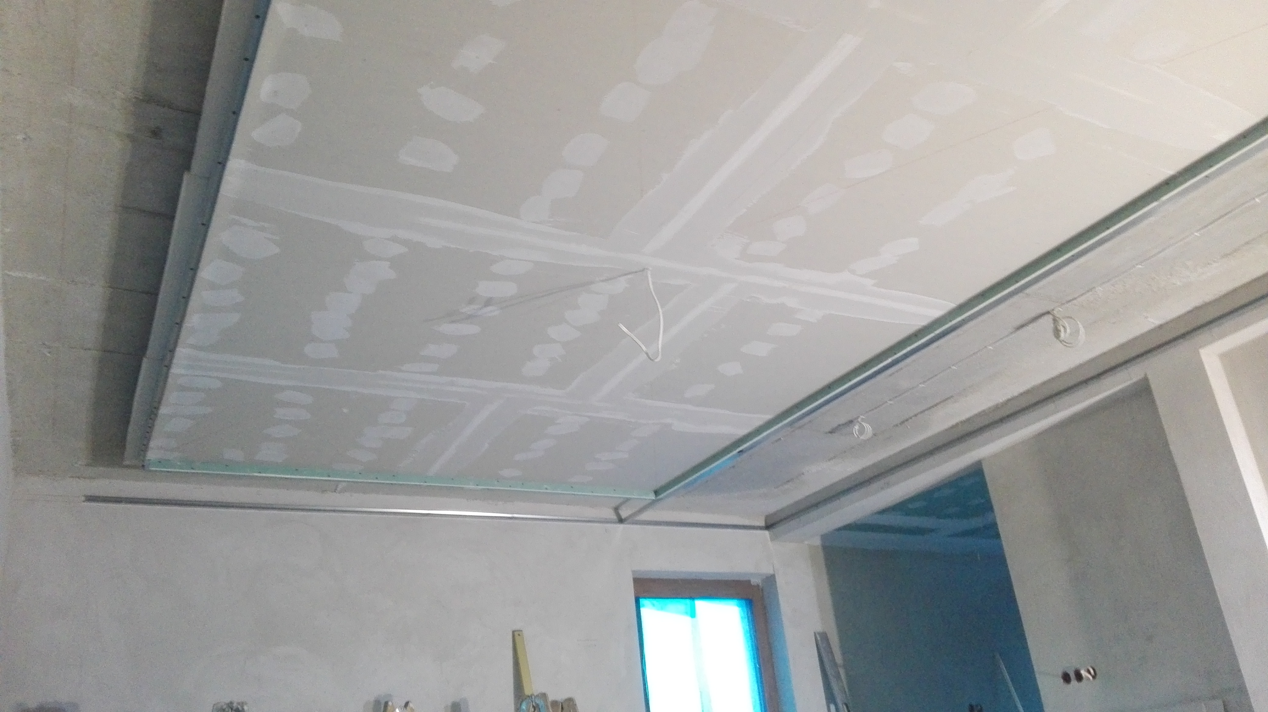 Sufit podwieszany z płyt gipsowo-kartonowych w trakcie szpachlowania, widoczne metalowe profile i wystające kable, Szepietowo.
