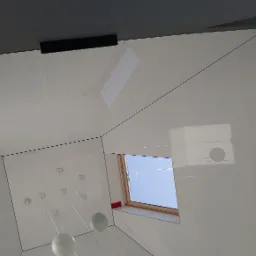 Nowoczesne, białe wnętrze poddasza z oknem dachowym, widok z dołu, minimalistyczny design, lampy wiszące na cienkich kablach.