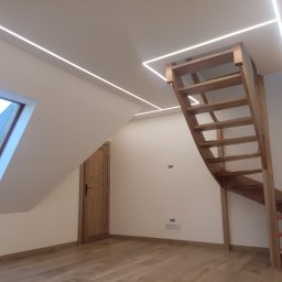 Firma REMONTOWO-BUDOWLANA Piotr Soltys - Poddasze po remoncie: drewniane schody, okno dachowe, oświetlenie LED. Widoczne gładkie ściany i panele podłogowe. Minimalistyczny design.