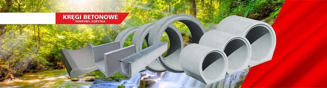 Betonowe kręgi, korytka i pokrywy na tle leśnego strumienia i czerwonego materiału reklamowego.