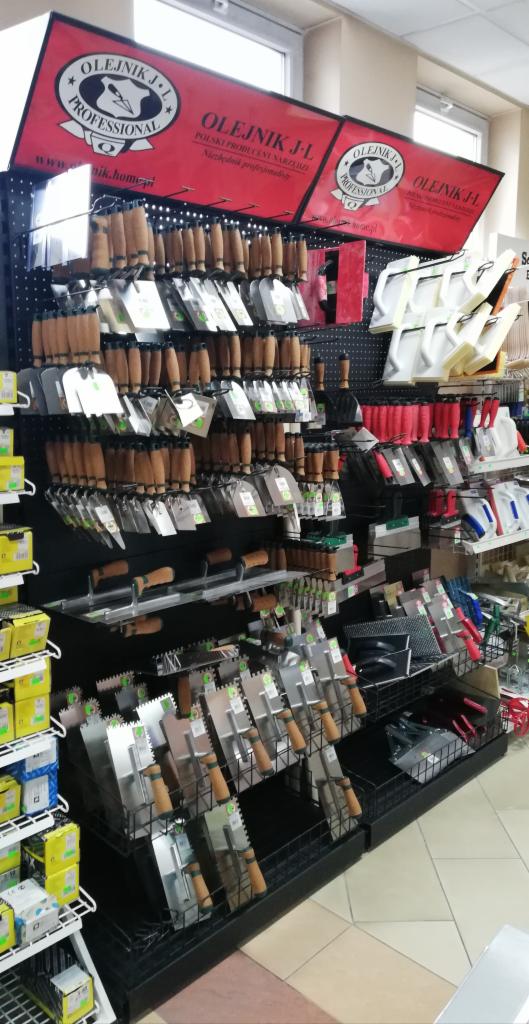 Ekspozycja w sklepie z narzędziami budowlanymi, głównie szpachle różnych rozmiarów i rodzajów, pod szyldem producenta Olejnik J.L.