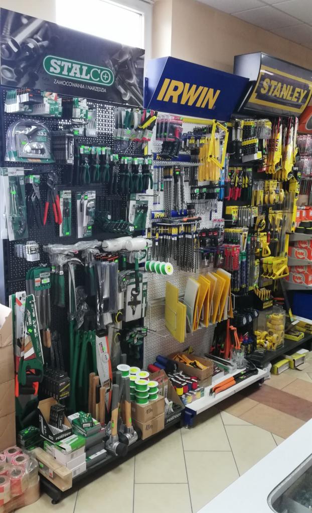 Ekspozycja narzędzi i akcesoriów budowlanych marek Stalco, Irwin i Stanley w sklepie, widoczne młotki, piły, szczypce, wiertła i inne przybory.