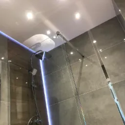 Nowoczesna kabina prysznicowa typu walk-in z szarymi płytkami i oświetleniem LED w suficie, zrealizowana w 15-572.