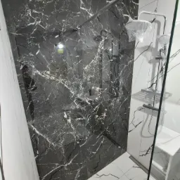 Elegancka kabina prysznicowa z czarnymi płytkami imitującymi marmur i białą armaturą. Nowoczesny design z widocznymi elementami chromowanymi.