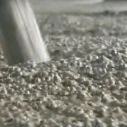 Wylewanie płynnej masy na podłoże podczas wykonywania wylewki, widoczne logo producenta materiału.