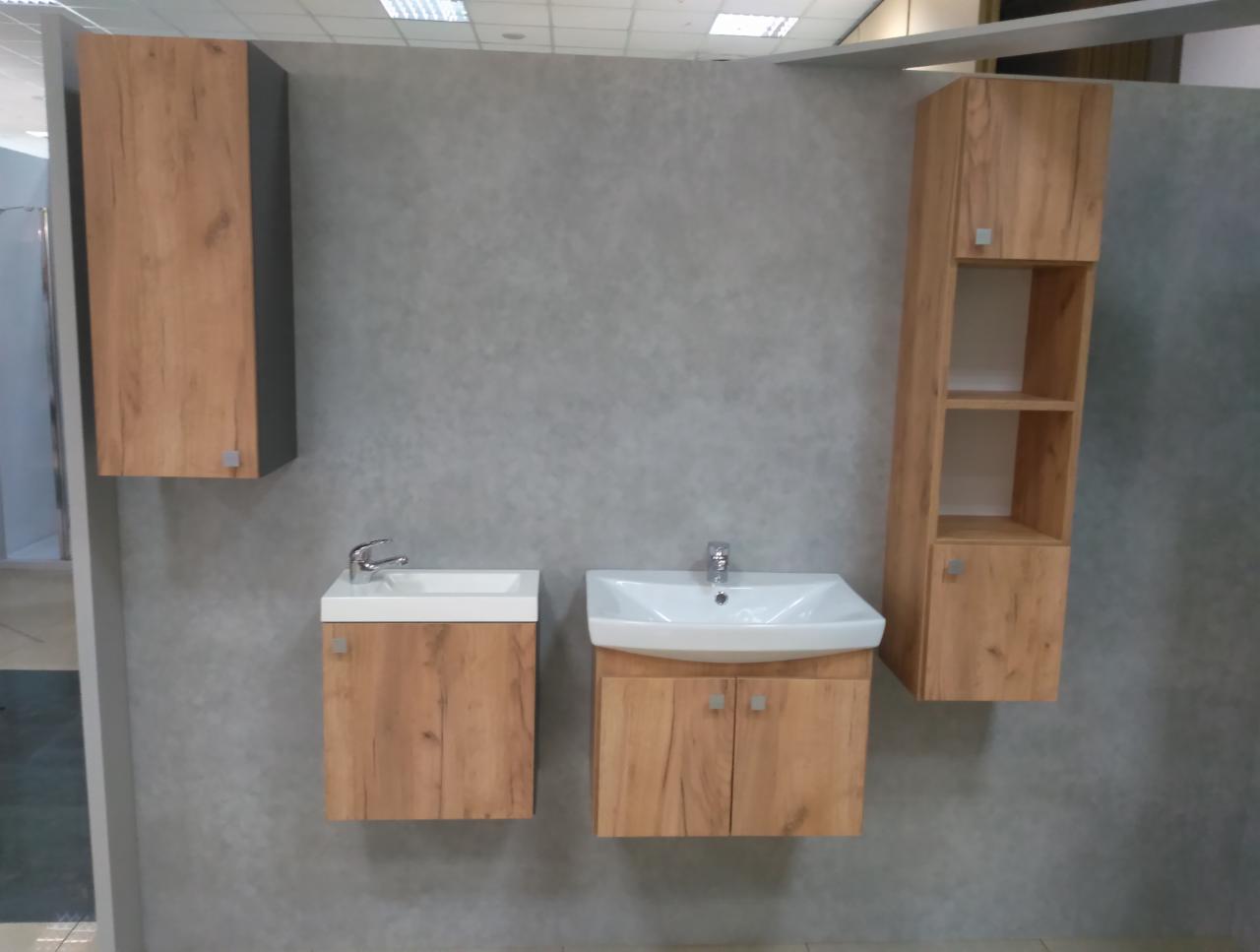 Zestaw szafek łazienkowych z umywalkami i wiszącymi szafkami w odcieniach drewna na tle szarej ściany.