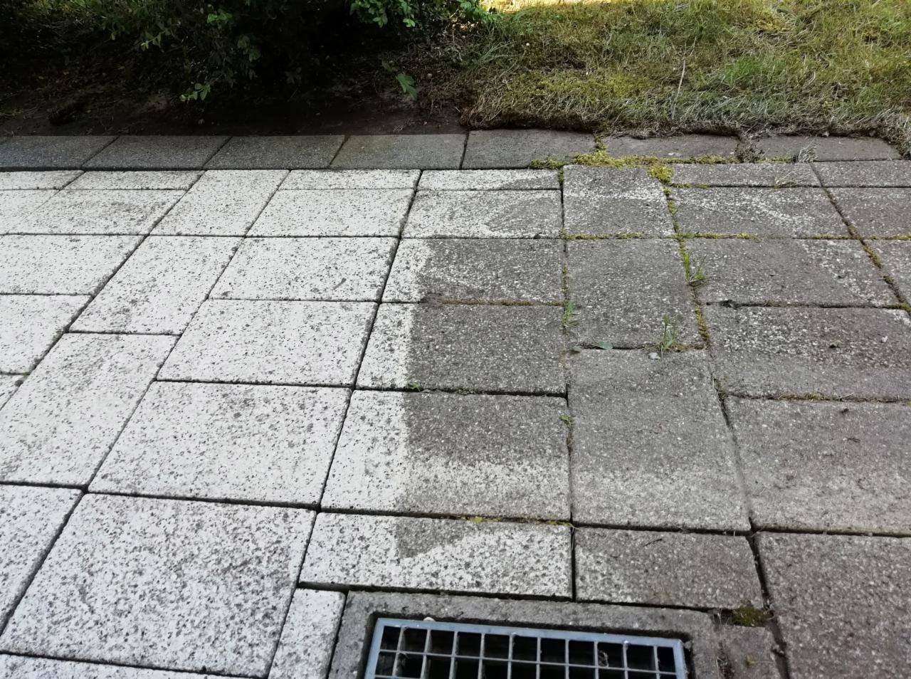 Częściowo wyczyszczona kostka brukowa z widocznym odpływem wody, kontrastujące powierzchnie przed i po czyszczeniu, minimalne pozostałości mchu w spoinach.