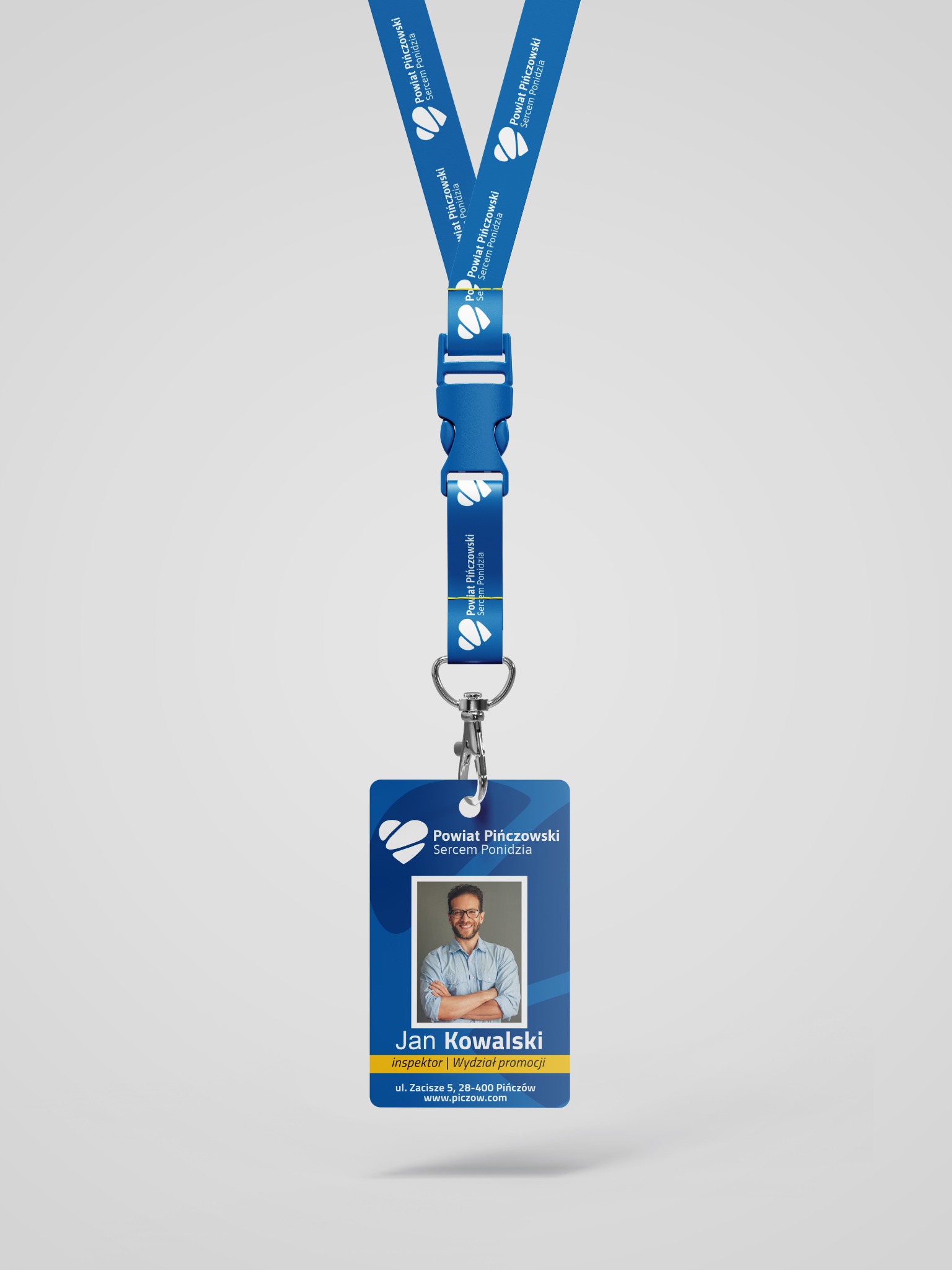 Identyfikator z niebieską smyczą z nadrukowanym logo i danymi Powiatu Pińczowskiego, zawierający zdjęcie pracownika Jan Kowalski, inspektor Wydziału Promocji.
