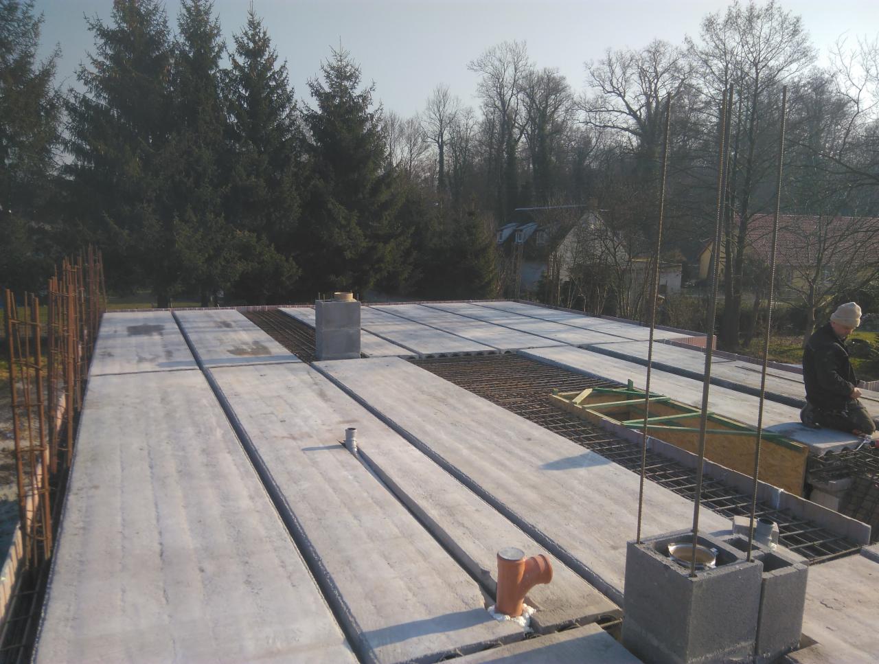 Wylany strop Teriva z pustakami betonowymi i zbrojeniem, widok z góry na budowę domu jednorodzinnego, w tle drzewa i zabudowania.