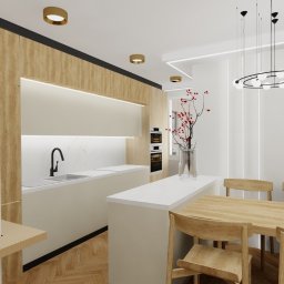 Project Group - Marzenna Cichocka - Jasna kuchnia z drewnianymi akcentami i okrągłą lampą. Na ścianie dekoracja z kół. Parkiet ułożony w jodełkę. Minimalistyczny design z wyspą kuchenną i stołem.