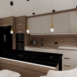 Project Group - Marzenna Cichocka - Wnętrze kuchni w odcieniach beżu i brązu z czarnym blatem. Nad blatem wiszą złote lampy. Na parapecie stoją zielone wazony. Widoczne krzesła barowe.