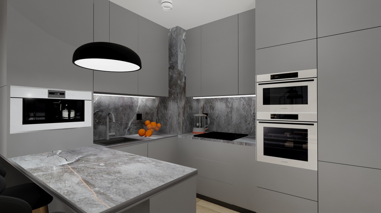 Minimalistyczna kuchnia w szarościach z blatem imitującym marmur. W tle marmurowa ściana, wbudowany piekarnik i owoce. Czarna lampa nad blatem.