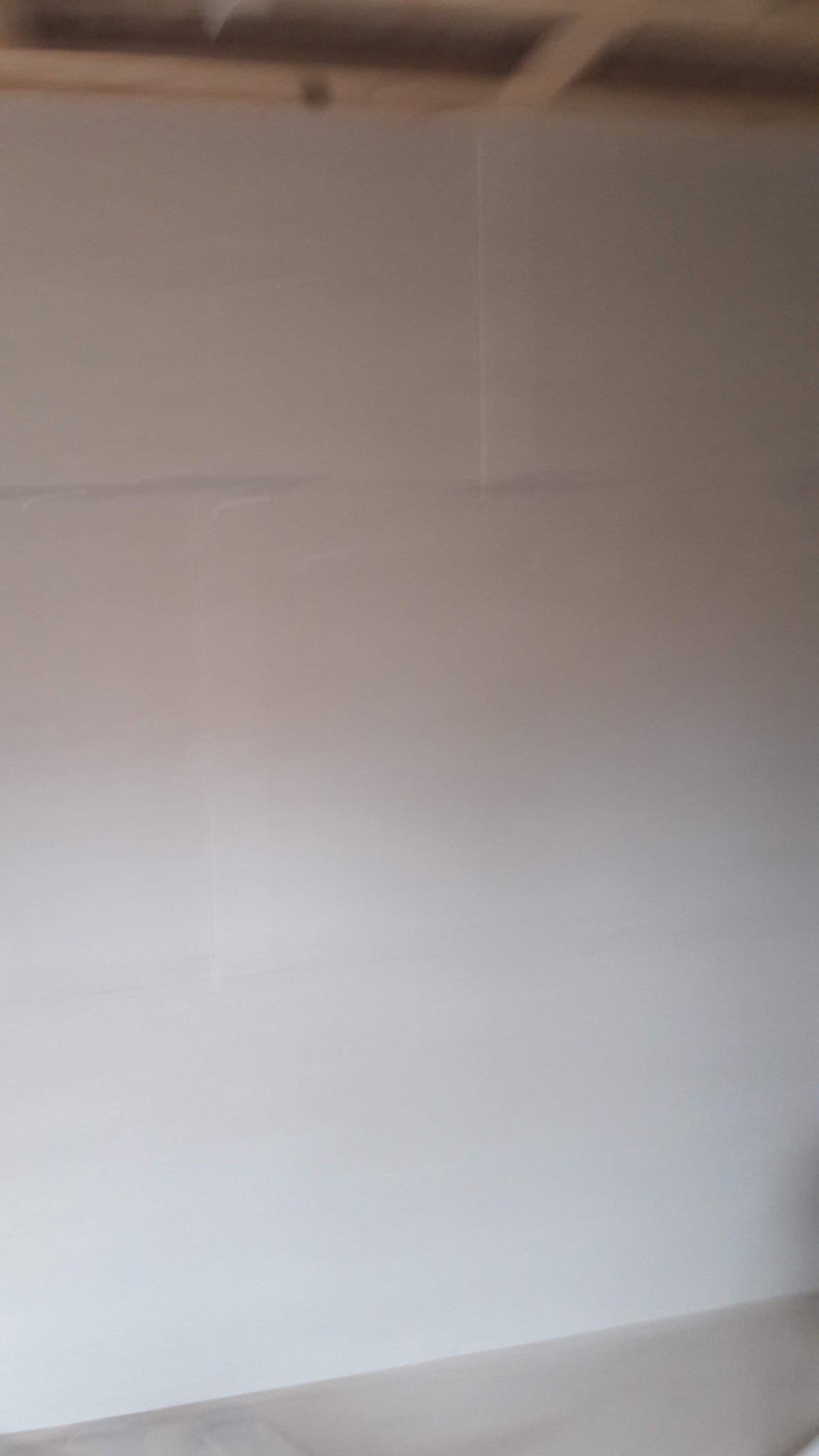 Świeżo położone, gładkie tynki na ścianie wewnętrznej, widoczne drewniane elementy konstrukcji sufitu.