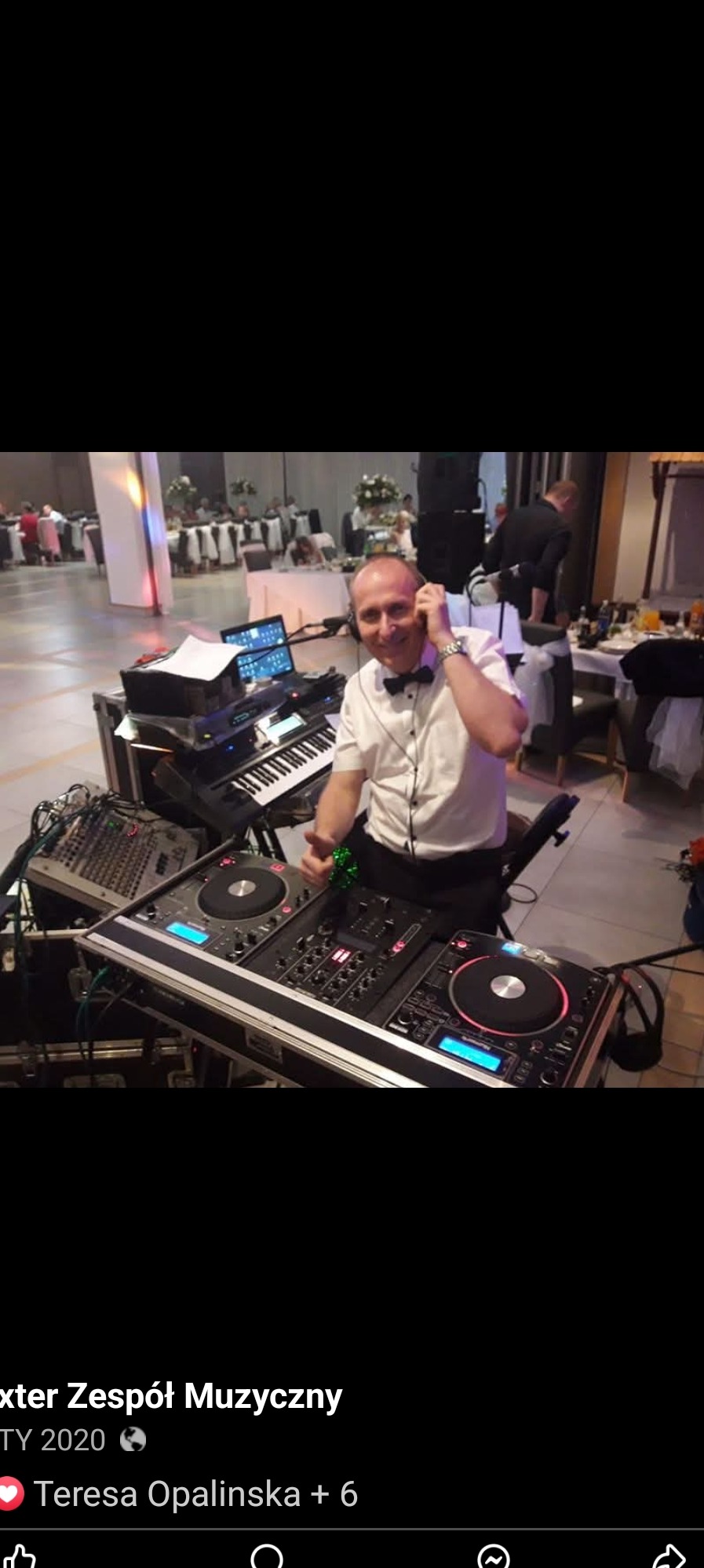 Uśmiechnięty DJ w muszce, z słuchawkami na uszach, prezentuje sprzęt DJ-ski na tle sali bankietowej z gośćmi.