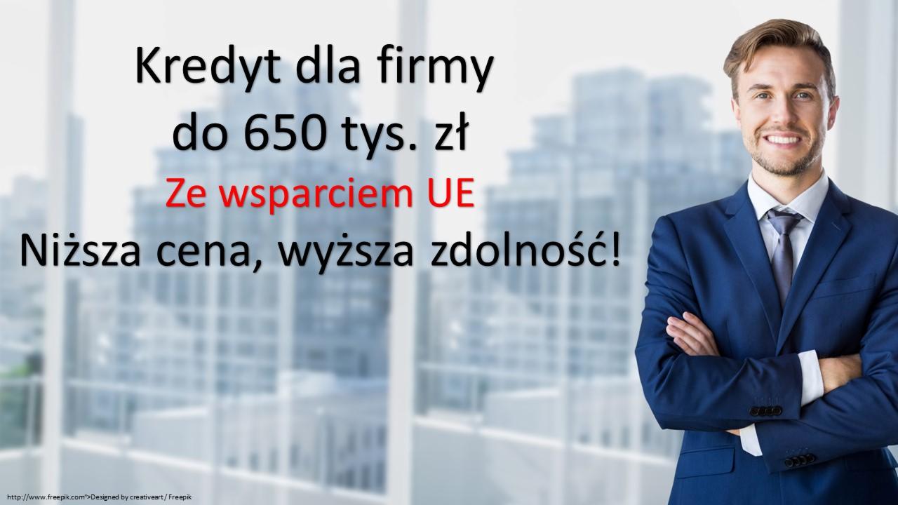 Uśmiechnięty mężczyzna w garniturze na tle okna z widokiem na miasto i napisem 'Kredyt dla firmy do 650 tys. zł. Ze wsparciem UE. Niższa cena, wyższa zdolność!'