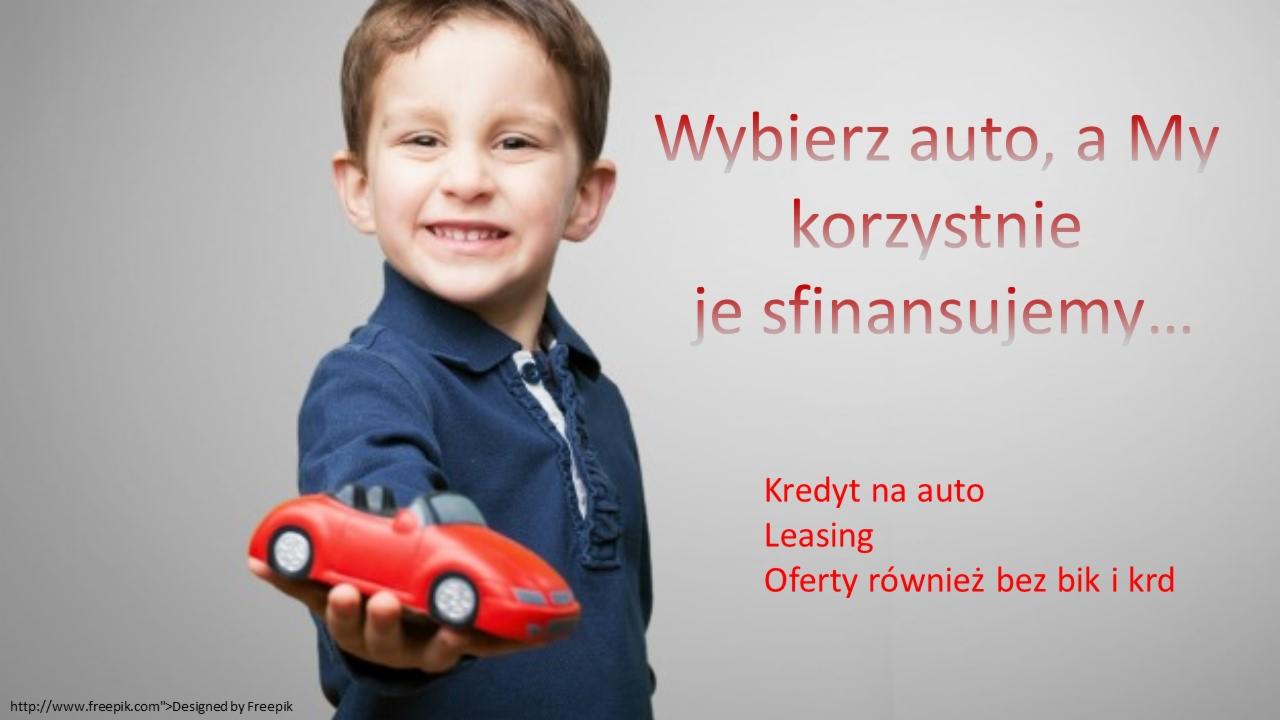 Uśmiechnięty chłopiec w granatowej koszuli prezentuje czerwoną zabawkę - model samochodu kabriolet, na tle tekstu zachęcającego do finansowania zakupu auta.