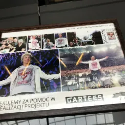 Oprawione zdjęcie kolażu z koncertu Bon Jovi na PGE Narodowym w Warszawie, 12.07.2019, z podziękowaniem za pomoc w realizacji projektu, z logo firmy GARTEES, prezentujące m.in. koszulki z nadrukiem...