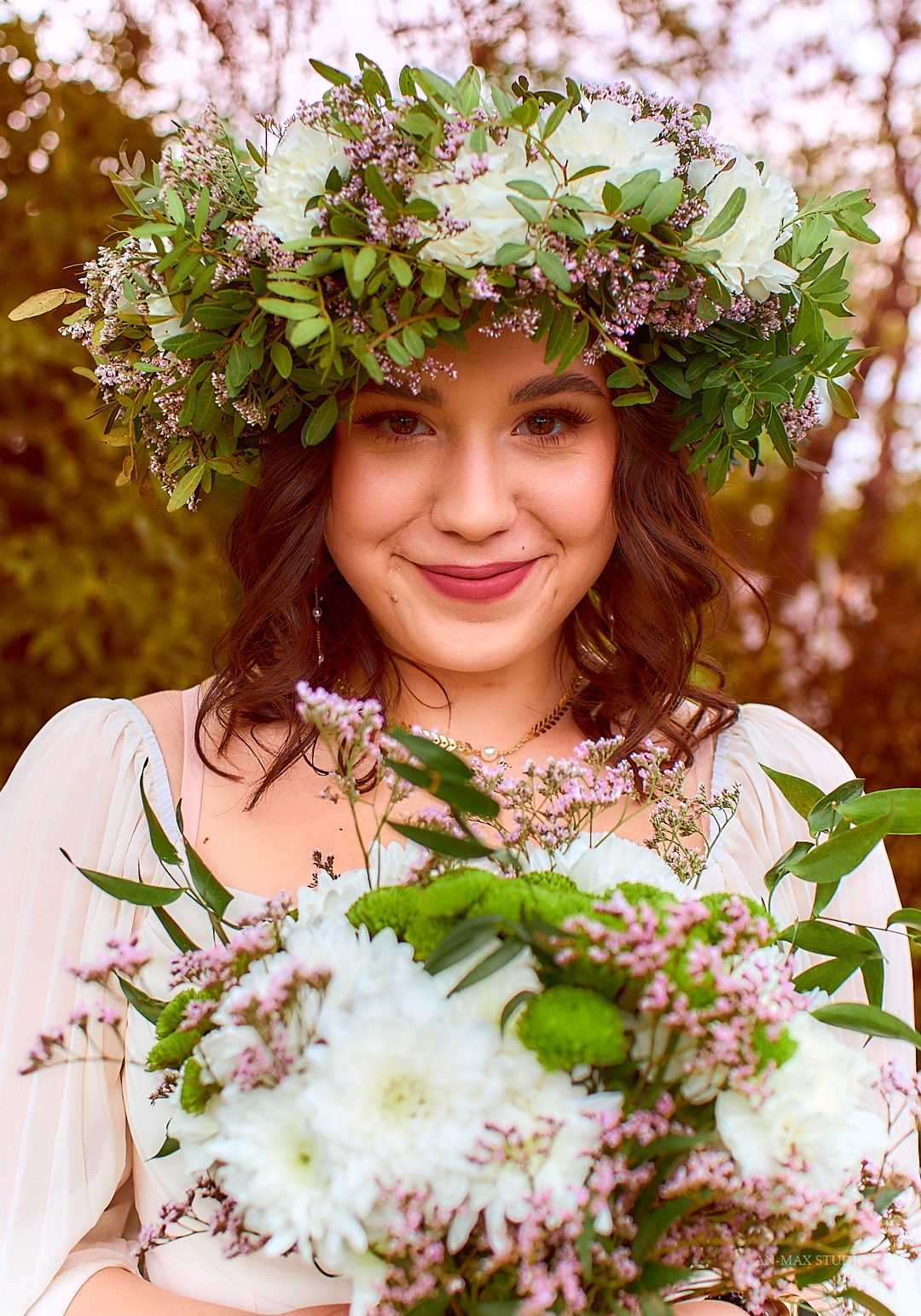 Portret uśmiechniętej kobiety z wiankiem i bukietem kwiatów w rękach, w plenerze. Romantyczna stylizacja i delikatny makijaż.