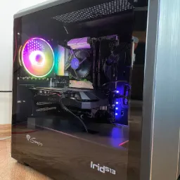 Komputer stacjonarny z przeszkloną obudową Genesis Irid 513, widoczne podzespoły: karta graficzna Gigabyte GeForce RTX, chłodzenie procesora Intel, pamięć RAM Ballistix, wentylator z tęczowym...