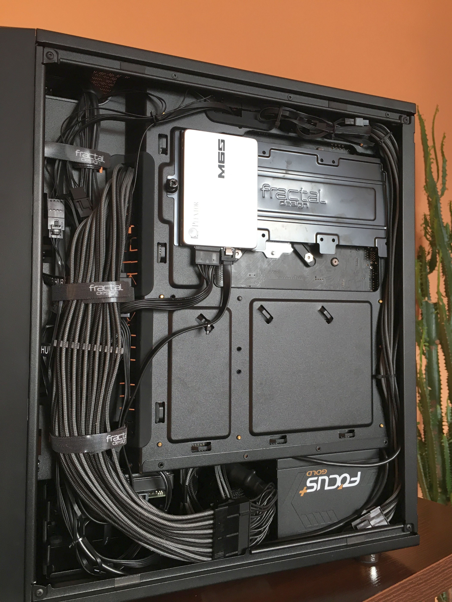 Wnętrze obudowy komputera stacjonarnego z uporządkowanym okablowaniem, widoczny dysk SSD marki Plextor M6S oraz zasilacz Seasonic Focus Gold, kable spięte opaskami Fractal Design.