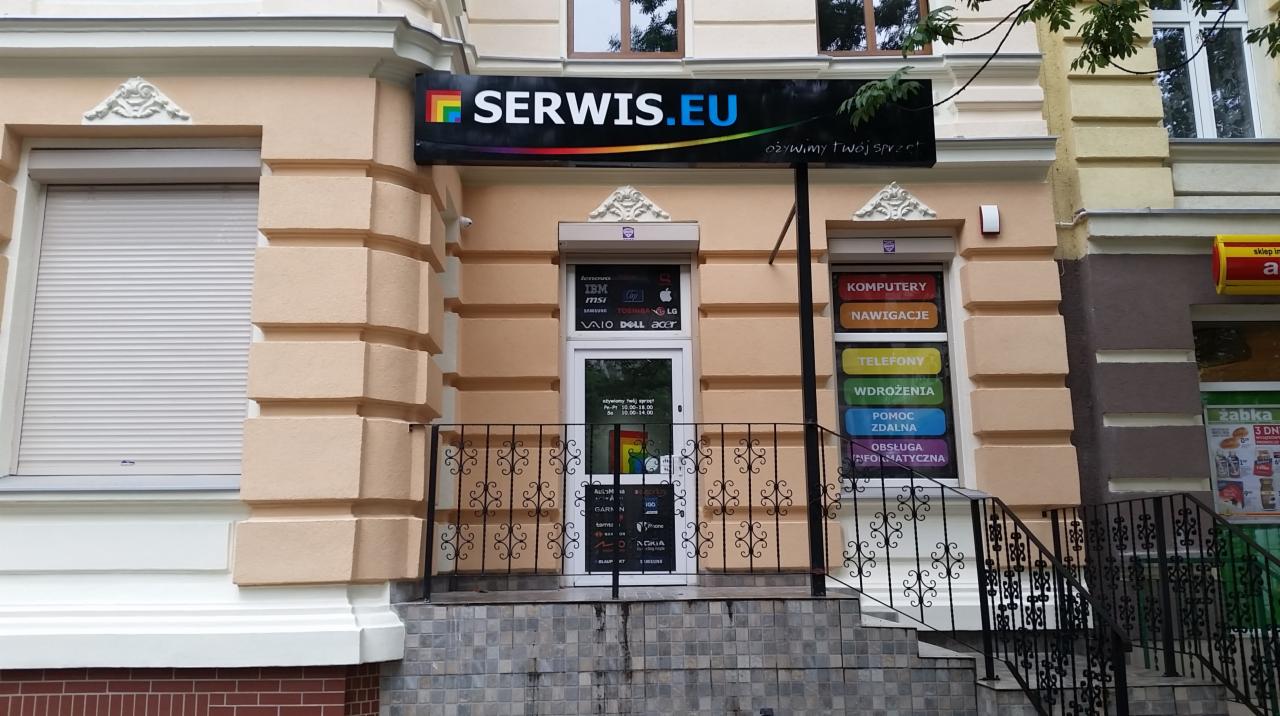 Fasada budynku z szyldem 'SERWIS.EU', oferującego naprawę komputerów, nawigacji, telefonów, wdrożenia, pomoc zdalną i obsługę informatyczną. Widoczne logo producentów sprzętu: IBM, MSI, VAIO, DELL,...