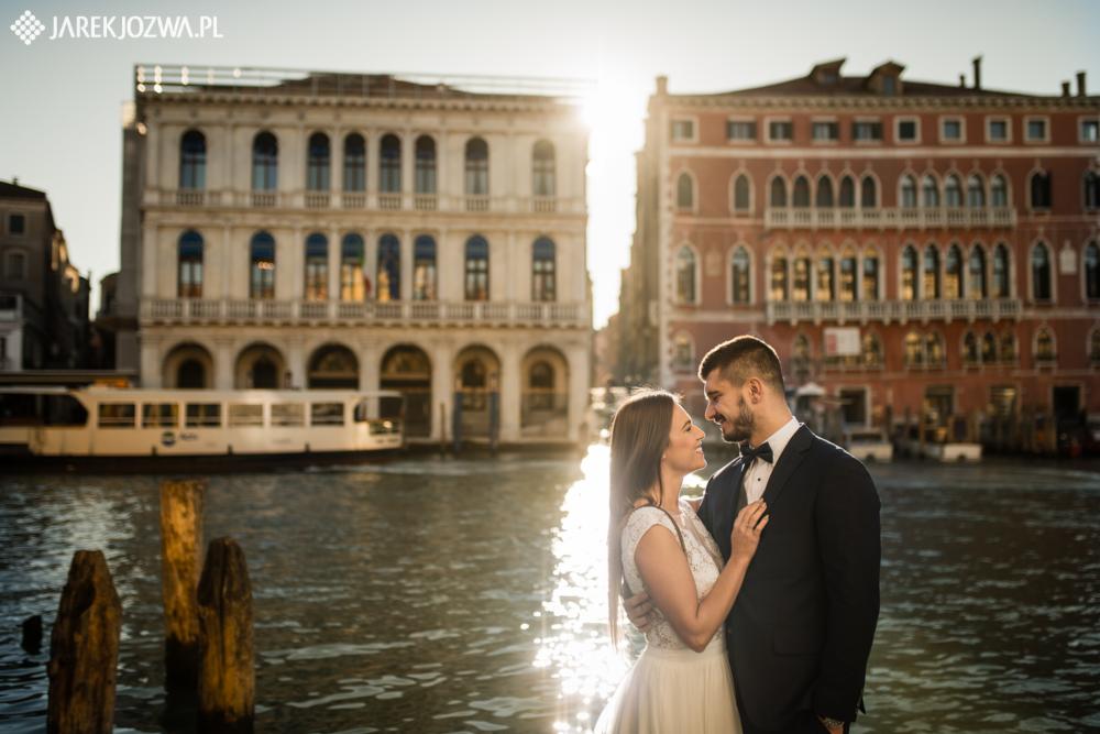 Para młoda w Wenecji, czuły uścisk na tle kanału z budynkami o architekturze renesansowej, promienie słońca odbijające się w wodzie.