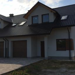 FPUH SALAMANDRA s.c. - Nowoczesny dom jednorodzinny z dwustanowiskowym garażem, ciemną dachówką i stolarką okienną w odcieniach brązu, widziany z poziomu chodnika.