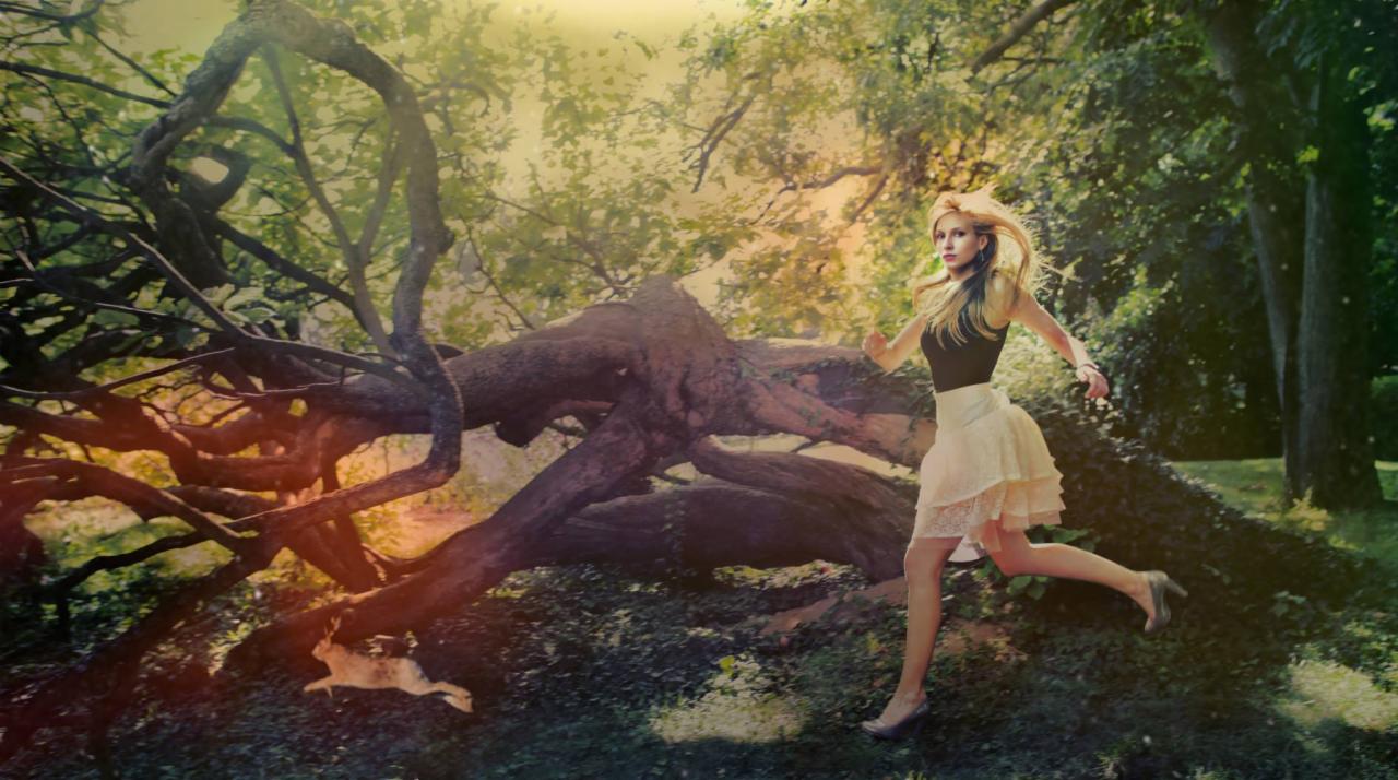 Blondwłosa kobieta w zwiewnej spódnicy ucieka przed królikiem w lesie, z powalonym drzewem w tle, w ciepłym, rozmytym świetle.