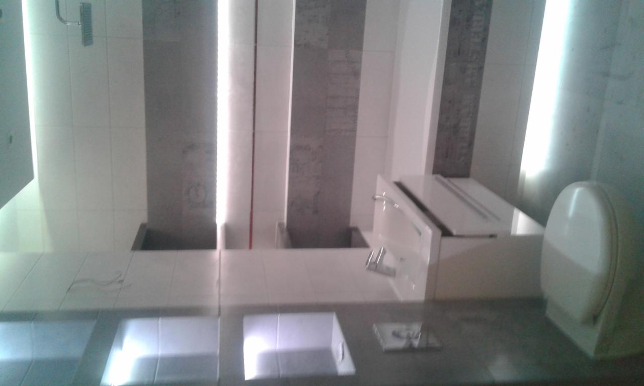 Nowoczesna łazienka z umywalkami wpuszczonymi w blat, szare płytki na ścianach i biała armatura.