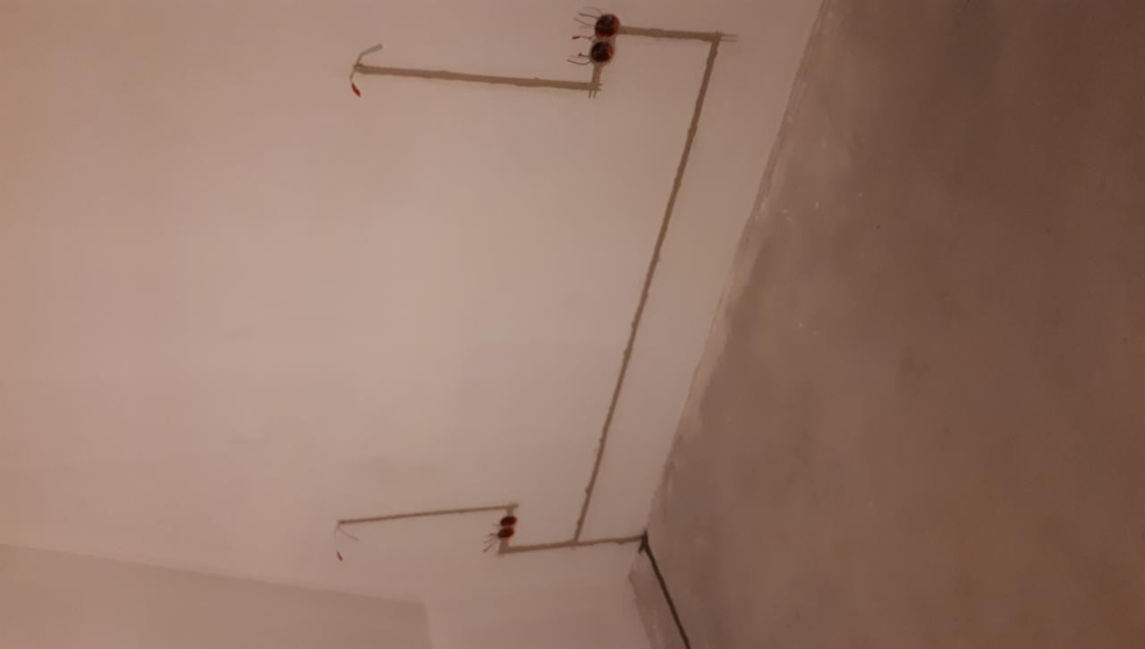 Świeżo położone kable elektryczne w bruzdach na suficie i ścianie, gotowe do dalszych prac instalacyjnych.