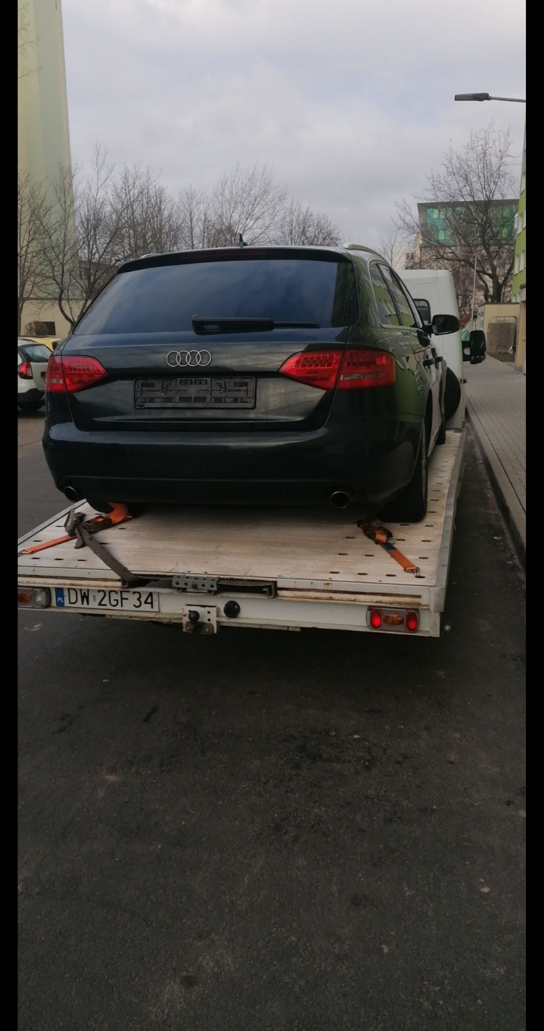 Czarny samochód Audi kombi zabezpieczony pasami transportowymi na platformie lawety, widok z tyłu, tablica rejestracyjna DW 2GF34.