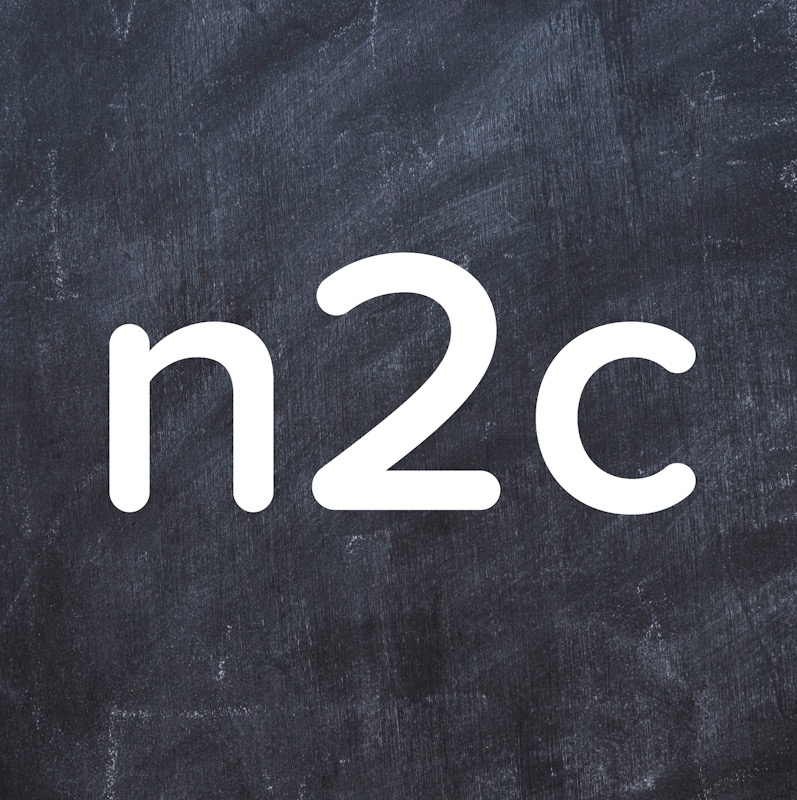 Białe litery 'n2c' na szorstkim, ciemnoszarym tle przypominającym tablicę kredową.