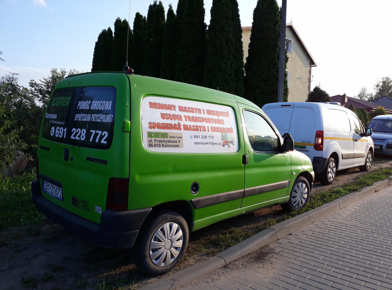 Zielony bus z naklejkami reklamującymi usługi naprawy i sprzedaży maszyn, oraz wypożyczalnię przyczep, zaparkowany na poboczu, z innymi pojazdami w tle.