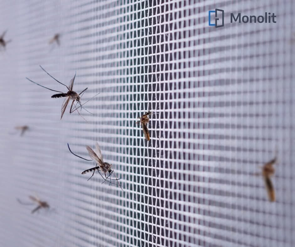 Siatka okienna z kilkoma martwymi komarami, logo firmy Monolit w prawym górnym rogu.