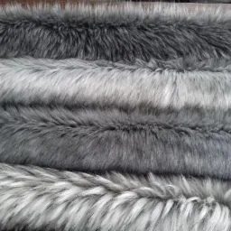 Różne odcienie szarego sztucznego futra ułożone warstwami, z widoczną strukturą włosia.