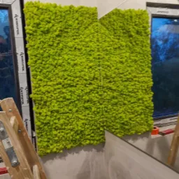 Montaż paneli z mchu na ścianie w łazience, widoczna drabina. Dekoracja wnętrza, naturalny akcent w nowoczesnym designie. Oświetlenie dzienne, okno w tle.