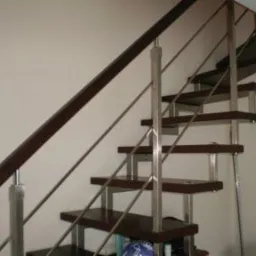 Nowoczesne schody z drewnianymi stopniami i balustradą ze stali nierdzewnej, widok z dołu, minimalistyczny design, jasne tło.