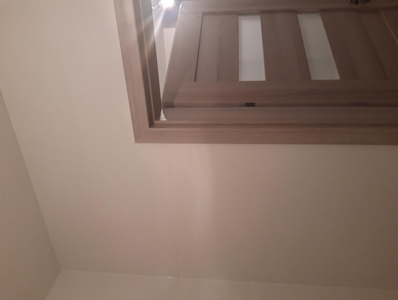 Zamontowane drzwi wewnętrzne z drewnianą ościeżnicą i trzema pionowymi szybami z mlecznego szkła, widoczne od dołu, na tle jasnej ściany.