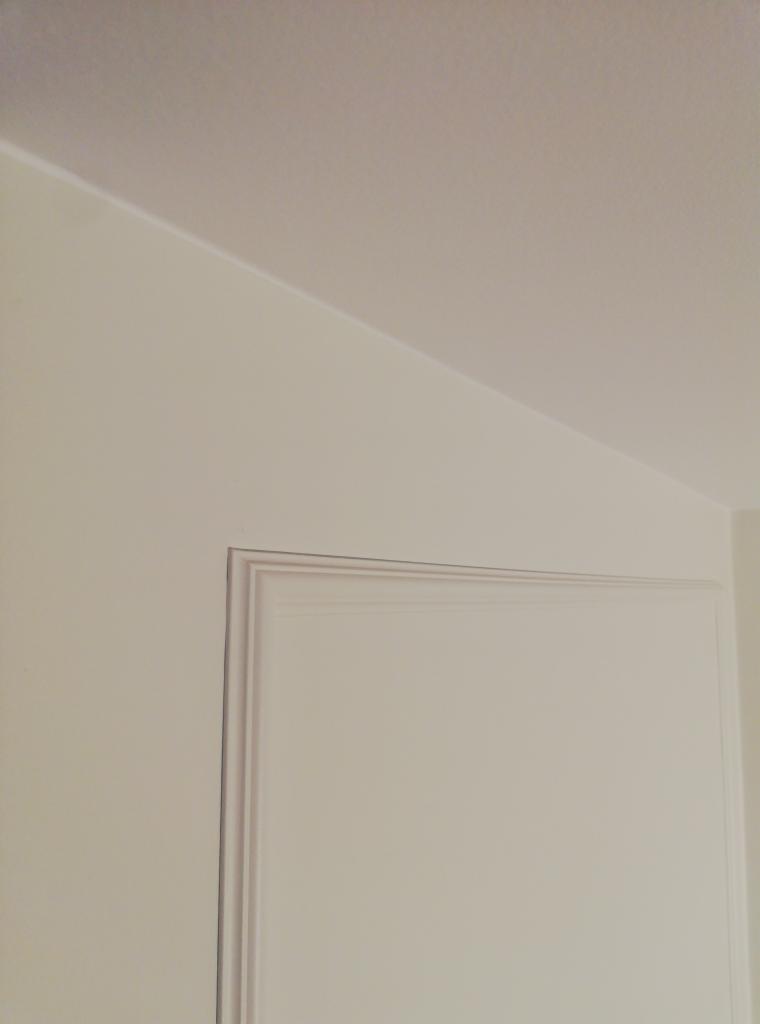Fragment ściany i sufitu po odświeżeniu, widoczny narożnik z subtelnym cieniowaniem i dekoracyjną listwą przysufitową.