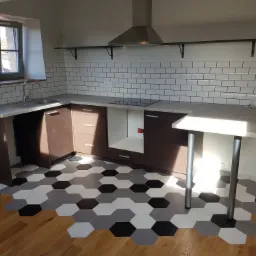 Wykończona kuchnia w Padwi Narodowej z heksagonalną podłogą przechodzącą z płytek w drewno, białe kafelki na ścianie i nowoczesny okap.