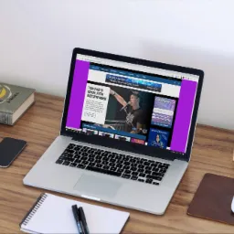 Laptop wyświetla stronę internetową portalu muzycznego NutaFM.pl, obok leżą książka, telefon, zegarek i głośnik.