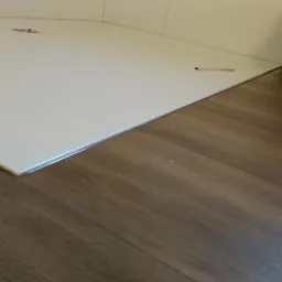 Połączenie białej, błyszczącej podłogi w łazience z panelami podłogowymi, widoczne detale wykończenia i fuga.