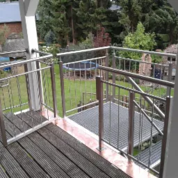 Metalowa balustrada z furtką na tarasie w Szczecinku, widok na zadbany ogród z trampoliną w tle.