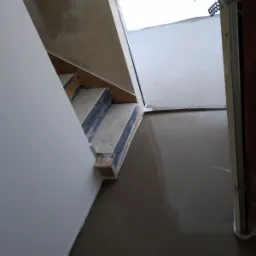 Schody w trakcie remontu, zabezpieczone folią, wylewka podłogowa w trakcie schnięcia, ściany przygotowane do malowania.