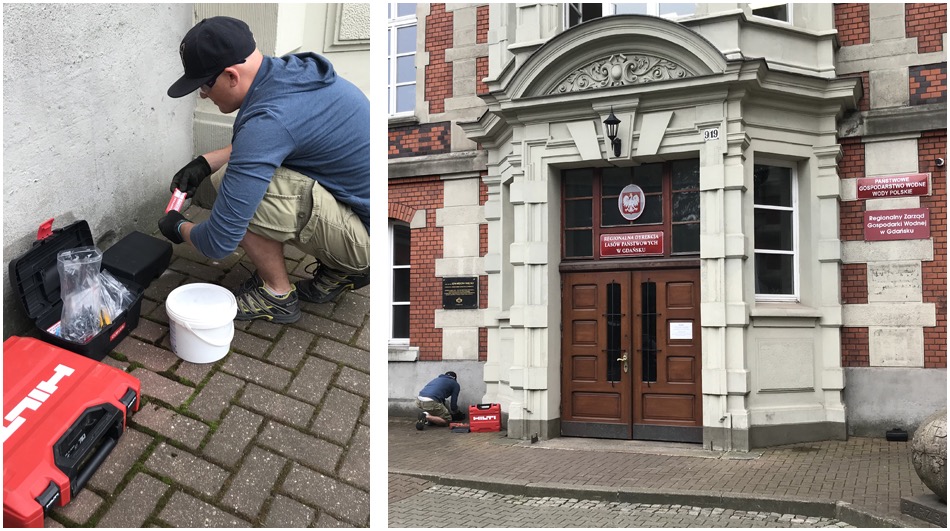 Pracownik w czarnych rękawicach przygotowuje preparat w pobliżu budynku administracyjnego z tablicami informacyjnymi, widoczna skrzynka narzędziowa Hilti i wiadro.