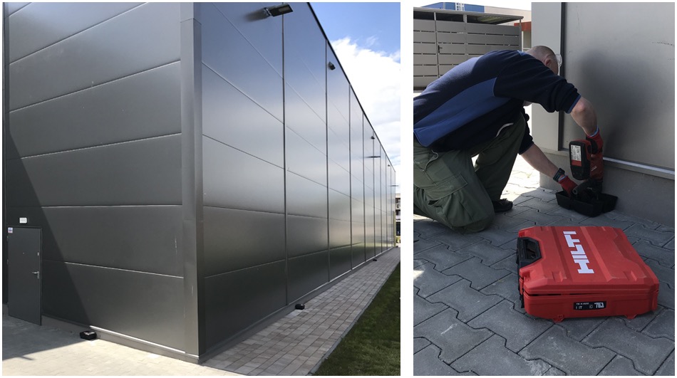 Montaż zabezpieczeń na elewacji budynku przemysłowego; pracownik wierci w elewacji w pobliżu kostki brukowej, obok czerwona skrzynka narzędziowa Hilti.