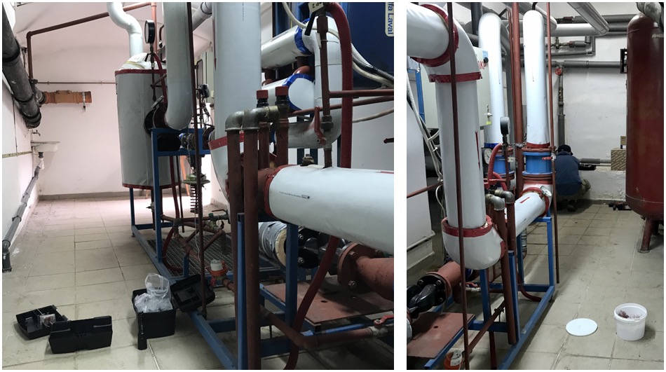 Instalacja przemysłowa z rurami i zbiornikami, widoczny pracownik w trakcie pracy, narzędzia w skrzynce obok.