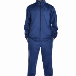 Mężczyzna w granatowym dresie sportowym z suwakiem, pozujący na białym tle w białych tenisówkach.